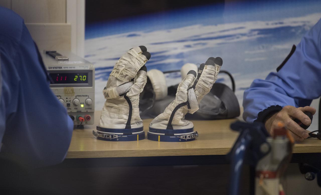 The Russian Sokol suit gloves of Expedition 60 Soyuz Commander Alexander Skvortsov of Rosprepares are seen on a table as he prepares to have his Russian Sokol suit pressure checked in preparation for launch aboard the Soyuz MS-13 spacecraft, Saturday, July 20, 2019 at the Baikonur Cosmodrome in Kazakhstan. launched aboard the Soyuz MS-13 spacecraft at 12:28 p.m. Eastern time (9:28 p.m. Baikonur time) on July 20 to begin their journey to the International Space Station. Photo Credit: (NASA/Joel Kowsky)