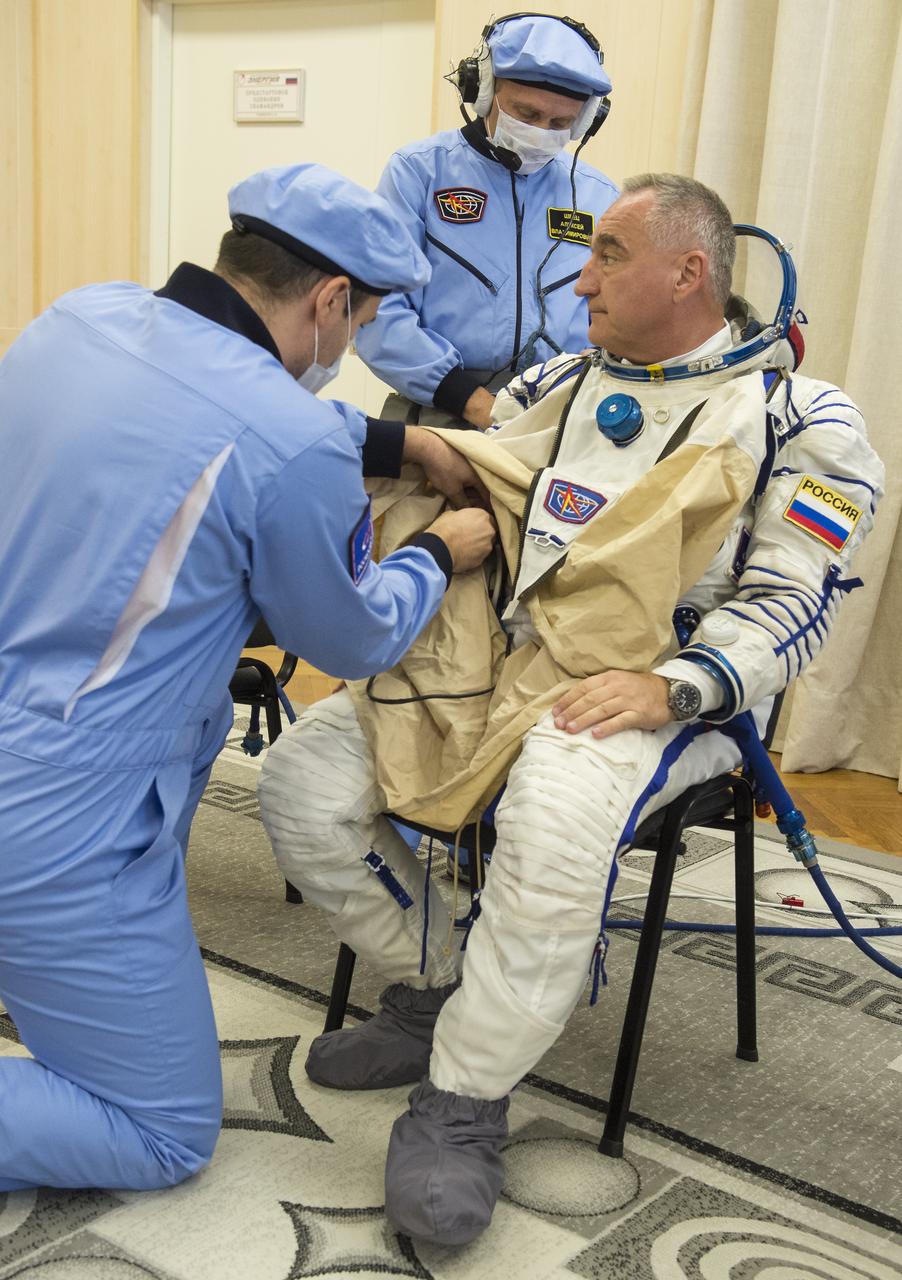 Expedition 60 Soyuz Commander Alexander Skvortsov of Roscosmos is helped into his Russian Sokol suit as he and fellow cremates Andrew Morgan of NASA and Luca Parmitano of ESA (European Space Agency) prepare for their Soyuz launch to the International Space Station Saturday, July 20, 2019 in Baikonur, Kazakhstan. Skvortsov, Andrew Morgan of NASA, and Luca Parmitano of ESA (European Space Agency) launched aboard the Soyuz MS-13 spacecraft at 12:28 p.m. Eastern time (9:28 p.m. Baikonur time) on July 20 to begin their journey to the orbiting laboratory. Photo Credit: (NASA/GCTC/Andrey Shelepin)