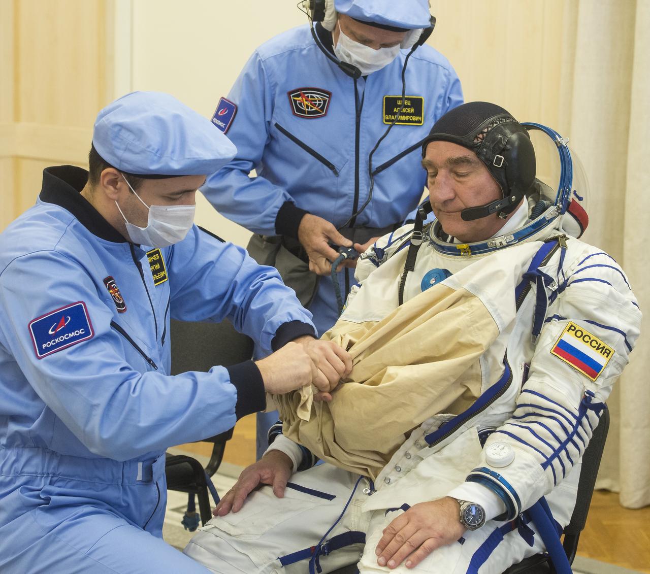 Expedition 60 Soyuz Commander Alexander Skvortsov of Roscosmos is helped into his Russian Sokol suit as he and fellow cremates Andrew Morgan of NASA and Luca Parmitano of ESA (European Space Agency) prepare for their Soyuz launch to the International Space Station Saturday, July 20, 2019 in Baikonur, Kazakhstan. Skvortsov, Andrew Morgan of NASA, and Luca Parmitano of ESA (European Space Agency) launched aboard the Soyuz MS-13 spacecraft at 12:28 p.m. Eastern time (9:28 p.m. Baikonur time) on July 20 to begin their journey to the orbiting laboratory. Photo Credit: (NASA/GCTC/Andrey Shelepin)