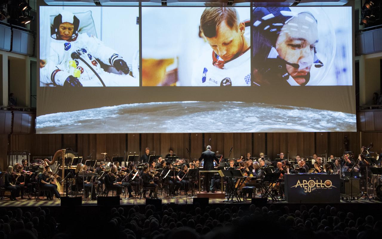Emil de Cou conducts the National Symphony Orchestra to a backdrop of Apollo 11 images during the "NSO Pops, Apollo 11: A 50th Anniversary, One Small Step, One Giant Leap" a program including musical acts, speakers, and images and video related to space, on Saturday, July 20, 2019 at the John F. Kennedy Center for the Performing Arts in Washington. NASA and the country are recognizing the 50th anniversary of Apollo 11, in which astronauts Neil Armstrong, Michael Collins, and Buzz Aldrin crewed the first mission to land astronauts on the Moon. Photo Credit: (NASA/Aubrey Gemignani)