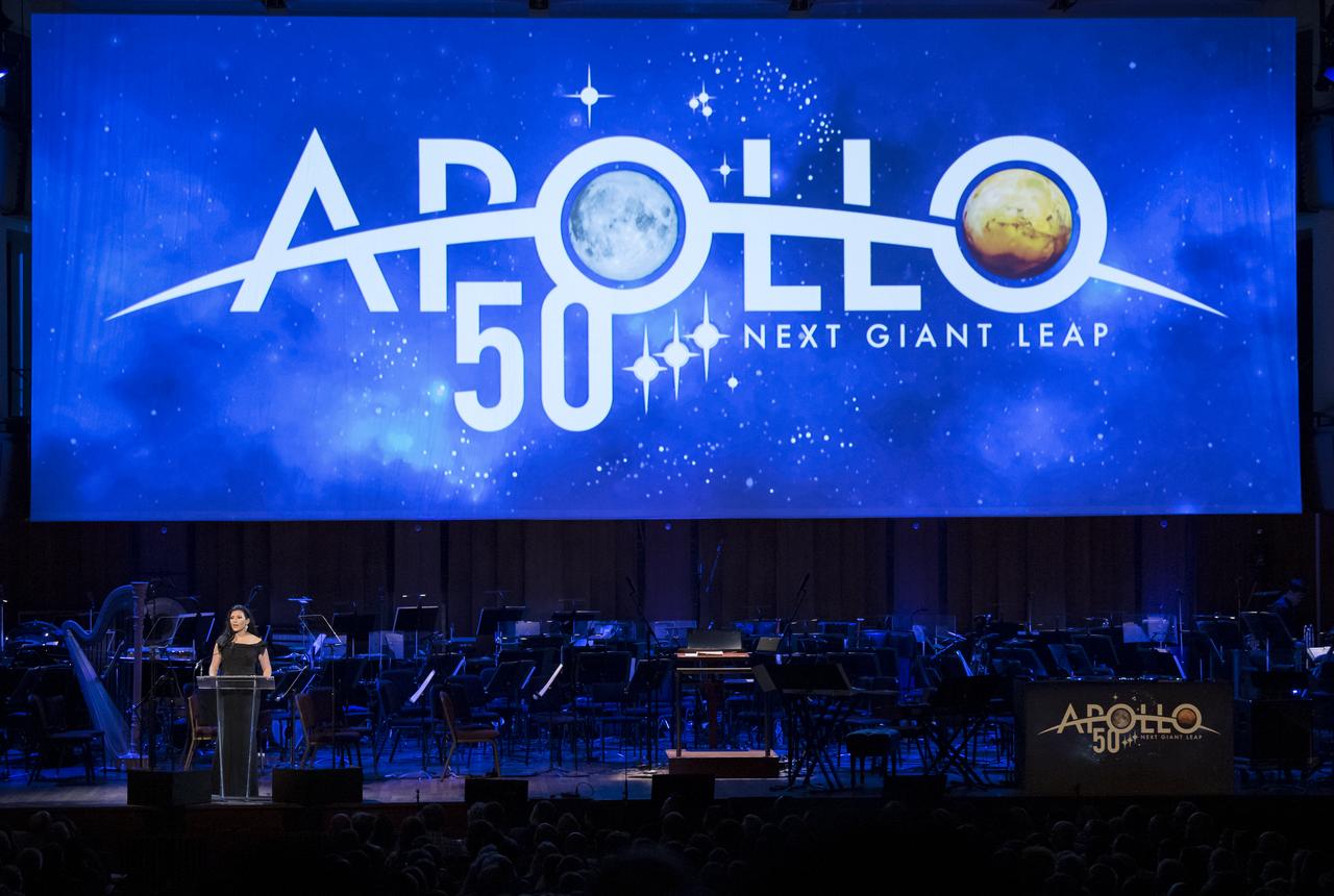 NASA Associate Administrator for Communications, Bettina Inclan speaks during the "National Symphony Orchestra Pops, Apollo 11: A 50th Anniversary, One Small Step, One Giant Leap" a program including musical acts, speakers, and images and video related to space, on Saturday, July 20, 2019 at the John F. Kennedy Center for the Performing Arts in Washington. NASA and the country are recognizing the 50th anniversary of Apollo 11, in which astronauts Neil Armstrong, Michael Collins, and Buzz Aldrin crewed the first mission to land astronauts on the Moon. Photo Credit: (NASA/Aubrey Gemignani)