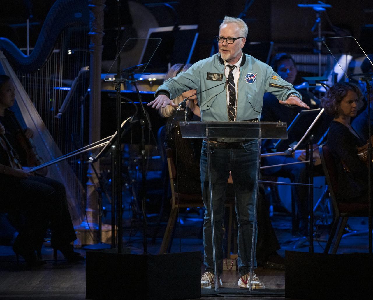 Maker and host of Savage Builds, Adam Savage, speaks during the "National Symphony Orchestra Pops, Apollo 11: A 50th Anniversary, One Small Step, One Giant Leap" a program including musical acts, speakers, and images and video related to space, on Saturday, July 20, 2019 at the John F. Kennedy Center for the Performing Arts in Washington. NASA and the country are recognizing the 50th anniversary of Apollo 11, in which astronauts Neil Armstrong, Michael Collins, and Buzz Aldrin crewed the first mission to land astronauts on the Moon. Photo Credit: (NASA/Aubrey Gemignani)