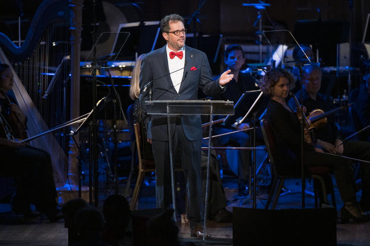 American composer Michael Giacchino speaks during the "National Symphony Orchestra Pops, Apollo 11: A 50th Anniversary, One Small Step, One Giant Leap" a program including musical acts, speakers, and images and video related to space, on Saturday, July 20, 2019 at the John F. Kennedy Center for the Performing Arts in Washington. NASA and the country are recognizing the 50th anniversary of Apollo 11, in which astronauts Neil Armstrong, Michael Collins, and Buzz Aldrin crewed the first mission to land astronauts on the Moon. Photo Credit: (NASA/Aubrey Gemignani)