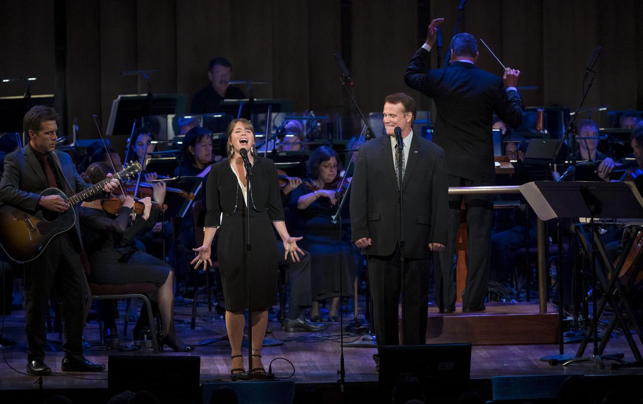 Son of Apollo 11 astronaut Neil Armstrong, Mark Armstrong, right, and his daughter, sing a song he wrote about his father, "Flight of Fancy," during the "National Symphony Orchestra Pops, Apollo 11: A 50th Anniversary, One Small Step, One Giant Leap" a program including musical acts, speakers, and images and video related to space, on Saturday, July 20, 2019 at the John F. Kennedy Center for the Performing Arts in Washington. NASA and the country are recognizing the 50th anniversary of Apollo 11, in which astronauts Neil Armstrong, Michael Collins, and Buzz Aldrin crewed the first mission to land astronauts on the Moon. Photo Credit: (NASA/Aubrey Gemignani)