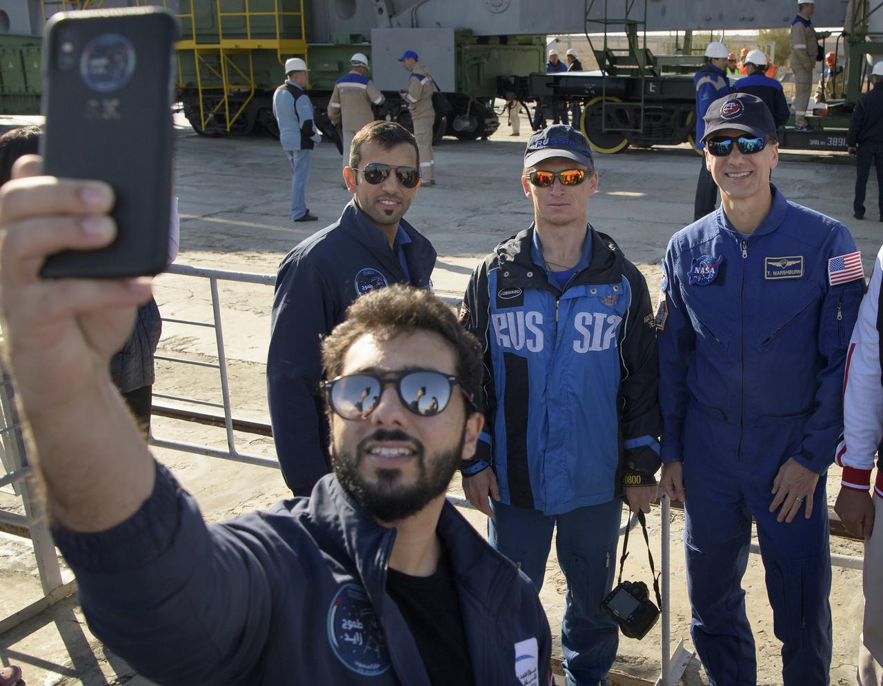 A guest takes a selfie with backup spaceflight participant Sultan Al-Neyadi of the United Arab Emirates, left, and Expedition 61 backup crewmembers Sergei Ryzhikov of Roscosmos and Thomas Marshburn of NASA, as the Soyuz rocket is rolled out by train to the launch pad, Monday, Sept. 23, 2019 at the Baikonur Cosmodrome in Kazakhstan. Expedition 61 crewmembers Jessica Meir of NASA and Oleg Skripochka of Roscosmos, and spaceflight participant Hazzaa Ali Almansoori of the United Arab Emirates will launch September 25th on the Soyuz MS-15 spacecraft from the Baikonur Cosmodrome to the International Space Station. Photo Credit: (NASA/Bill Ingalls)