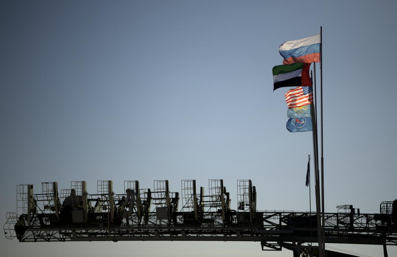 The flags of Russia, United Arab Emirates, United States of America, Kazakhstan and Roscosmos fly at the launch pad as the Soyuz rocket is raised into vertical position on the launch pad, Monday, Sept. 23, 2019 at the Baikonur Cosmodrome in Kazakhstan. Expedition 61 crewmembers Jessica Meir of NASA, Oleg Skripochka of Roscosmos, and spaceflight participant Hazzaa Ali Almansoori of the United Arab Emirates will launch September 25th on the Soyuz MS-15 spacecraft from the Baikonur Cosmodrome to the International Space Station. Photo Credit: (NASA/Bill Ingalls)