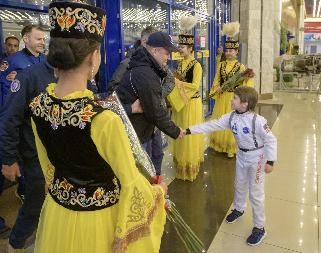 Girls in ceremonial Kazakhstan attire, and a local young man in a space outfit, welcome the return of Expedition 60 crew members Nick Hague of NASA and Alexey Ovchinin of Roscosmos, along with visiting astronaut Hazzaa Ali Almansoori of the United Arab Emirates at a Karaganda Airport welcome ceremony in Kazakhstan on Thursday, Oct. 3, 2019. Hague and Ovchinin are returning after 203 days in space where they served as members of the Expedition 59 and 60 crews onboard the International Space Station. Almansoori logged 8 days in space during his first flight as an astronaut. Photo Credit: (NASA/Bill Ingalls)