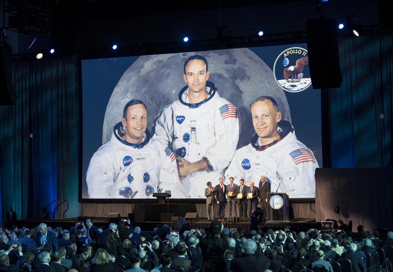 Seishiro Kibee on behalf of the International Astronautical Federation Awards Committee, left, NASA Administrator Jim Bridenstine, Luke Newell, grandson of Apollo 11 command module pilot Michael Collins, Mark Armstrong, son of Apollo 11 commander Neil Armstrong, and Apollo 11 lunar module pilot Buzz Aldrin, and Jean-Yves Le Gall, President of International Astronautical Federation (IAF), right, pose for a picture after the 2019 World Space Award was presented to the Apollo 11 crew during the opening ceremony of the 70th International Astronautical Congress, Monday, Oct. 21, 2019 at the Walter E. Washington Convention Center in Washington. Photo Credit: (NASA/Joel Kowsky)