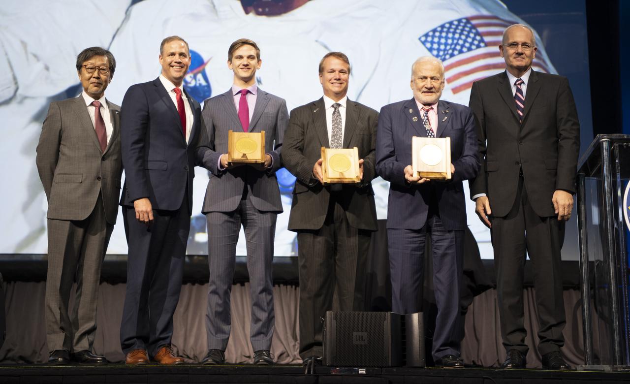 Seishiro Kibee on behalf of the International Astronautical Federation Awards Committee, left, NASA Administrator Jim Bridenstine, Luke Newell, grandson of Apollo 11 command module pilot Michael Collins, Mark Armstrong, son of Apollo 11 commander Neil Armstrong, and Apollo 11 lunar module pilot Buzz Aldrin, and Jean-Yves Le Gall, President of International Astronautical Federation (IAF), right, pose for a picture after the 2019 World Space Award was presented to the Apollo 11 crew during the opening ceremony of the 70th International Astronautical Congress, Monday, Oct. 21, 2019 at the Walter E. Washington Convention Center in Washington. Photo Credit: (NASA/Bill Ingalls)