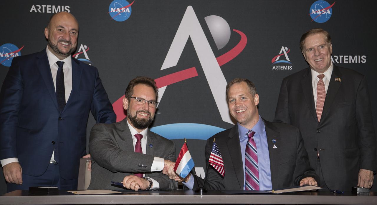 NASA Administrator Jim Bridenstine, right, and Dr. Marc Serres, chief executive officer, Luxembourg Space Agency (LSA), left, shake hands after signing an agreement while the Honorable James Randolph Evans, Ambassador to the Grant Duchy of Luxembourg, back right, and Etienne Schneider, Deputy Prime Minister, back left, observed at the 70th International Astronautical Congress, Tuesday, Oct. 22, 2019 in Washington. Photo Credit: (NASA/Aubrey Gemignani)
