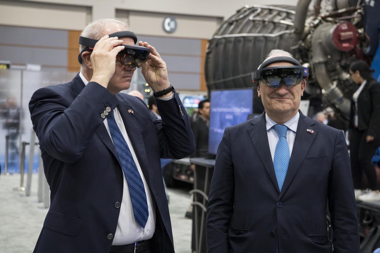 Philippe Étienne, French Ambassador to the U.S., right, and Jean-Yves Le Gall, president of the French space agency, National Centre for Space Studies (CNES), left, try virtual reality viewers at the NASA exhibit during the 70th International Astronautical Congress, Wednesday, Oct. 23, 2019, at the Walter E. Washington Convention Center in Washington. Photo credit: (NASA/Aubrey Gemignani)