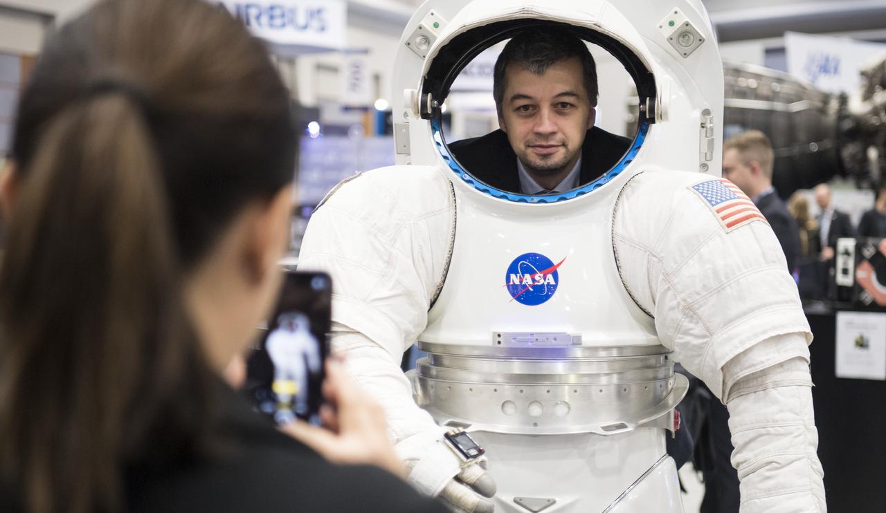 Visitors to the NASA exhibit at the 70th International Astronautical Congress take a picture in a mockup of a space suit, Friday, Oct. 25, 2019, at the Walter E. Washington Convention Center in Washington. Photo Credit: (NASA/Joel Kowsky)