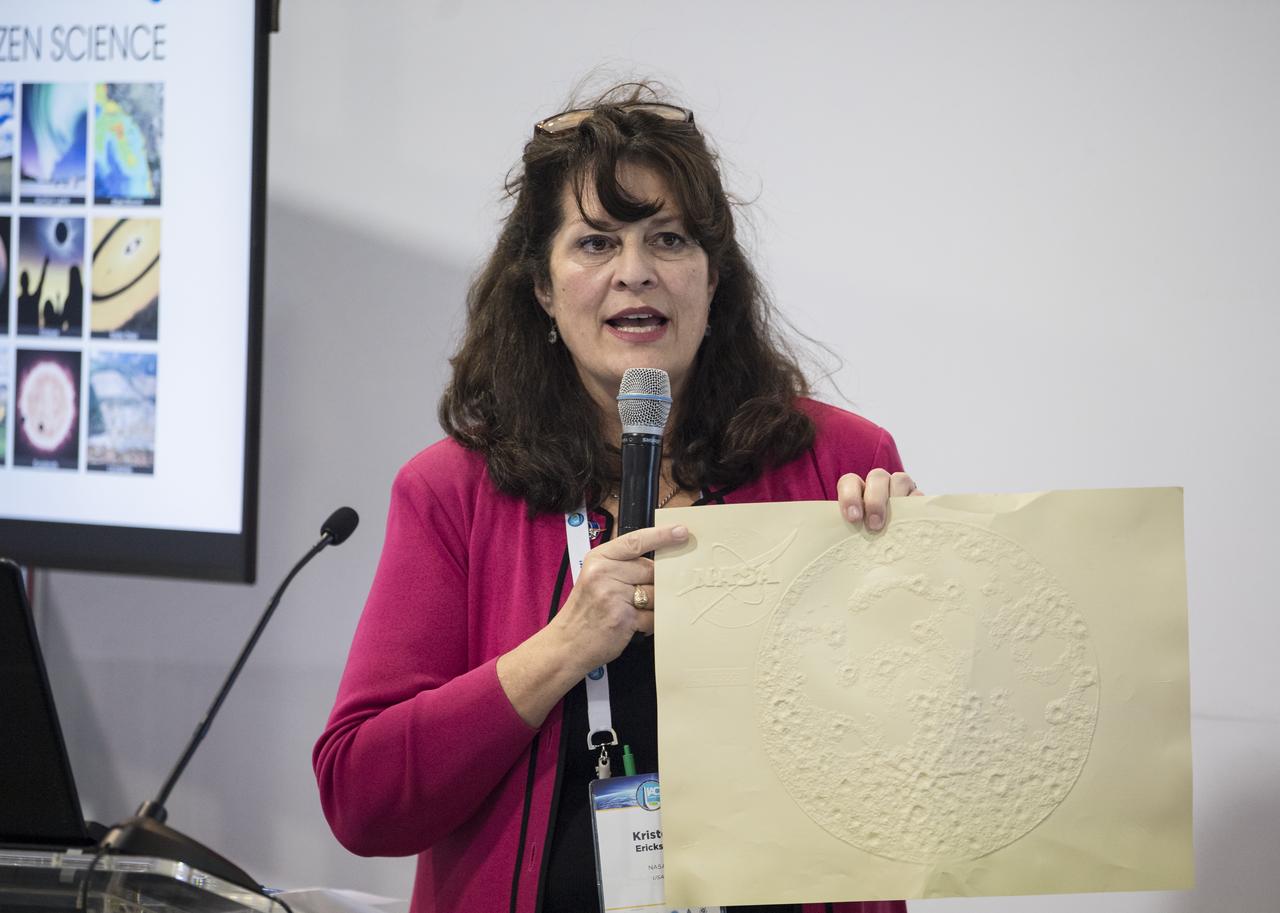 NASA's Kristen Erickson holds up a braille image of the NASA logo and the moon during a talk about educational science resources at the 70th International Astronautical Congress, Friday, Oct. 25, 2019, at the Walter E. Washington Convention Center in Washington. Photo credit: (NASA/Aubrey Gemignani)