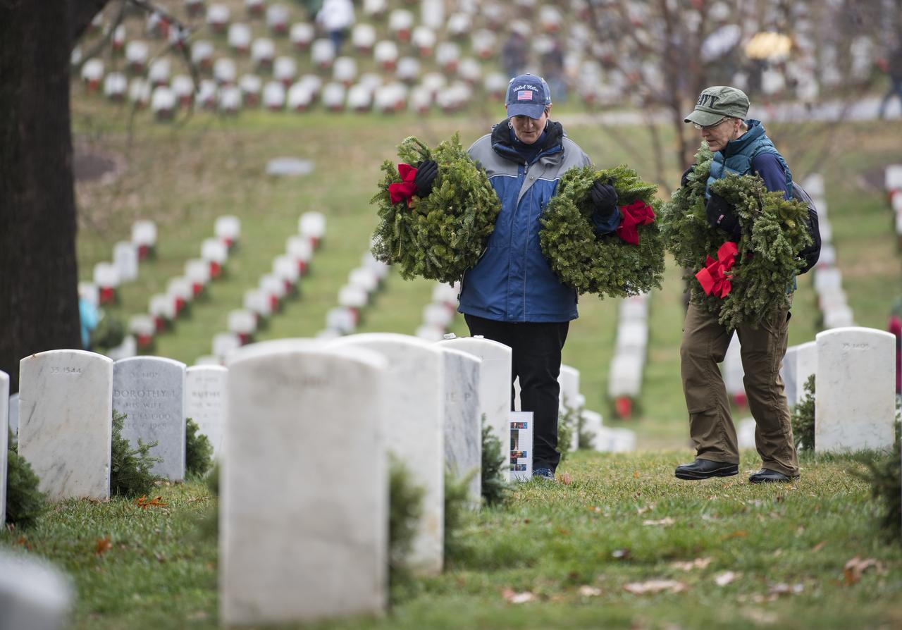 Visitors stop to look at the headstone of former astronaut and U.S. Senator John Glenn on National Wreaths Across America Day at Arlington National Cemetery, Sat., Dec. 14, 2019 in Arlington, Va. National Wreaths Across America Day is held annually to celebrate the lives of military veterans. NASA astronaut Doug Wheelock attended to honor those who lost their lives in the quest for space exploration as well as fellow service members.  Photo Credit: (NASA/Aubrey Gemignani)