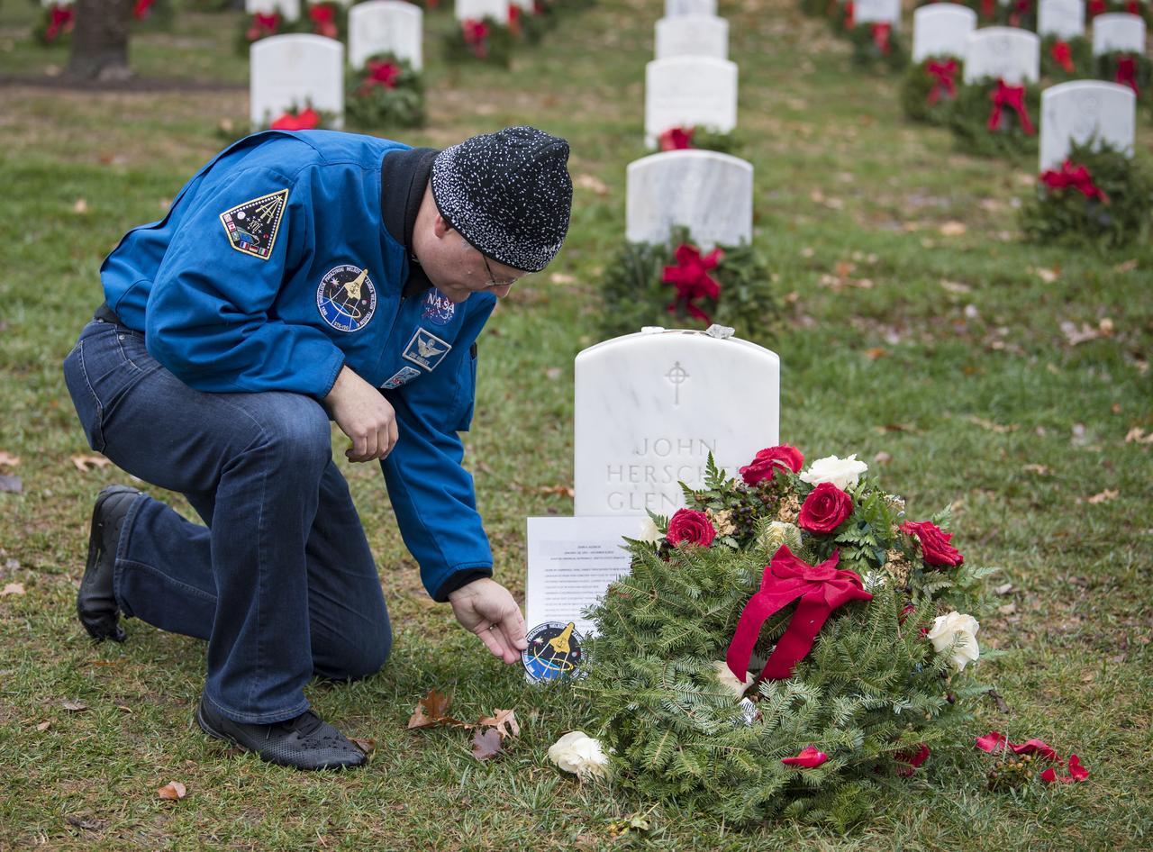 NASA astronaut Doug Wheelock leaves his STS-120 mission patch at the gravesite of former astronaut and U.S. Senator John Glenn during National Wreaths Across America Day at Arlington National Cemetery, Sat., Dec. 14, 2019 in Arlington, Va. National Wreaths Across America Day is held annually to celebrate the lives of military veterans and wreaths are placed at the foot of every headstone. Wheelock honored those who lost their lives in the quest for space exploration as well as fellow service members. Photo Credit: (NASA/Aubrey Gemignani)