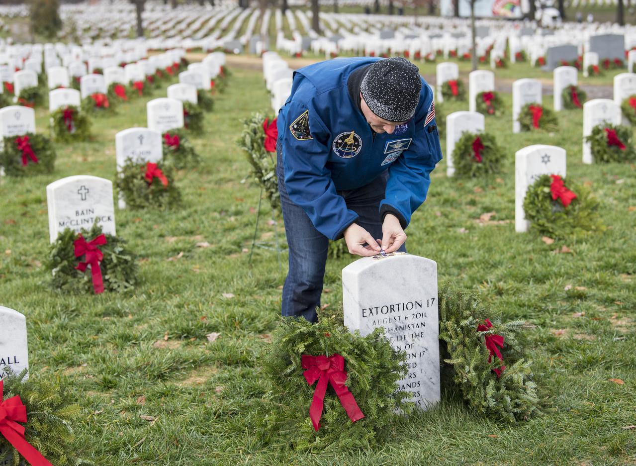 NASA astronaut Doug Wheelock leaves a NASA pin on the headstone of the Extortion 17, fellow service members who lost their lives during his tour of duty in Afghanistan, as part of National Wreaths Across America Day, Sat., Dec. 14, 2019 at Arlington National Cemetery in Arlington, Va. National Wreaths Across America Day is held annually to celebrate the lives of military veterans. Wheelock honored those who lost their lives in the quest for space exploration as well as fellow service members. Photo Credit: (NASA/Aubrey Gemignani)