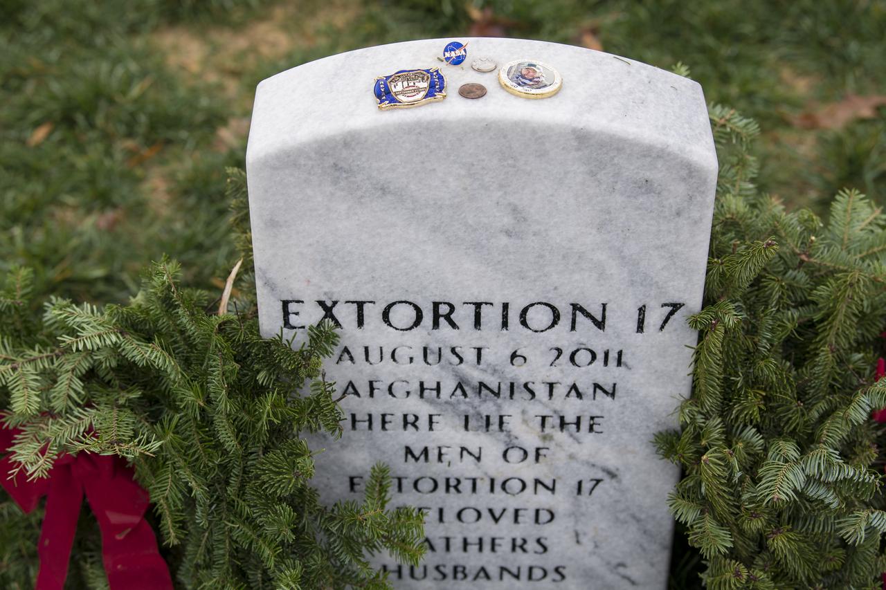 On National Wreaths Across America Day, items are seen on top of the headstone of the Extortion 17, service members who lost their lives during a tour of duty in Afghanistan, Sat., Dec. 14, 2019 at Arlington National Cemetery in Arlington, Va. National Wreaths Across America Day is held annually to celebrate the lives of military veterans. NASA astronaut Doug Wheelock served with the Extortion 17 and honored them as well as those who lost their lives in the quest for space exploration by laying wreaths at their headstones and at the memorial sites. Photo Credit: (NASA/Aubrey Gemignani)