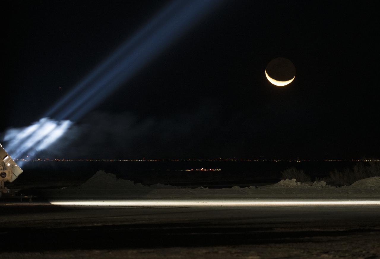 The moon is seen behind the spotlight that will follow the Boeing CST-100 Starliner as it lands in White Sands, New Mexico, Sunday, Dec. 22, 2019. The spacecraft is scheduled to land around 5:57am after an abbreviated Orbital Flight Test for the company that still meets several mission objectives for NASA’s Commercial Crew program. The Starliner spacecraft launched on a United Launch Alliance Atlas V rocket at 6:36 a.m. Friday, Dec. 20 from Space Launch Complex 41 at Cape Canaveral Air Force Station in Florida. Photo Credit: (NASA/Aubrey Gemignani)