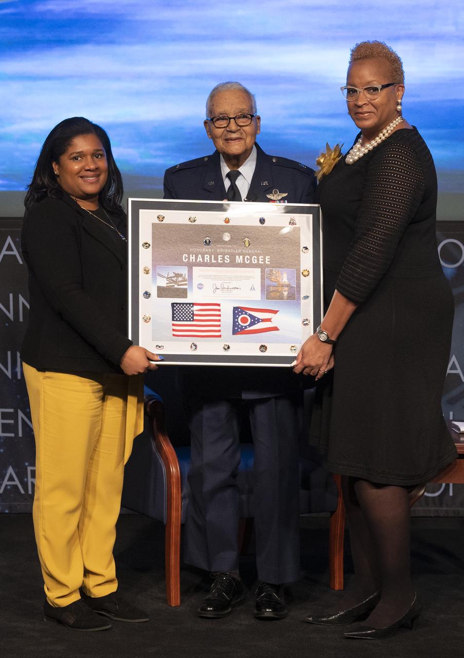 Zudayyah Taylor-Dunn, president of the NASA Headquarters Chapter of Blacks in Government (BIG), left, and LaVerne Randolph, vice president of the NASA Headquarters Chapter of BIG, present a montage containing an American Flag and Ohio State flag flown in space to Retired U.S. Air Force Honorary Brigadier General Charles McGee during a Black History Month program titled “Trailblazers, The Story of a Tuskegee Airman,” Wednesday, Feb. 5, 2020, at NASA Headquarters in Washington, DC. McGee, a pilot with the Tuskegee Airmen during World War II, was a career officer in the Air Force also serving during the Korean and Vietnam Wars. Over his 30 years of service he flew 409 combat missions. Of the 355 Tuskegee pilots who flew in combat, McGee is one of only nine surviving. Photo Credit: (NASA/Joel Kowsky)