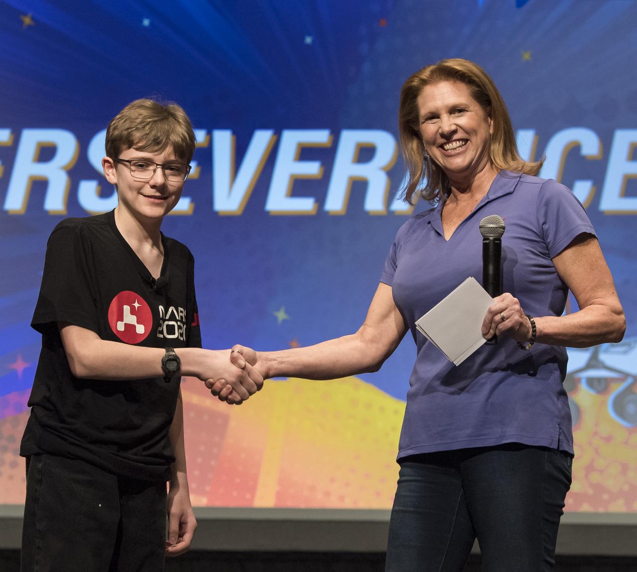 Lori Glaze, Director of the Planetary Science Division of NASA's Science Mission Directorate, right, shakes hands with Alex Mather, center, the student whose submission, Perseverance, was chosen as the official name of the Mars 2020 rover, Thursday, March 5, 2020, at Lake Braddock Secondary School in Burke, Va. The final selection of the new name was made by Associate Administrator of NASA's Science Mission Directorate, Thomas Zurbuchen, left, following a nationwide naming contest conducted in 2019 that drew more than 28,000 essays by K-12 students from every U.S. state and territory. Perseverance is currently at NASA's Kennedy Space Center in Florida being prepared for launch this summer. Photo Credit: (NASA/Aubrey Gemignani)