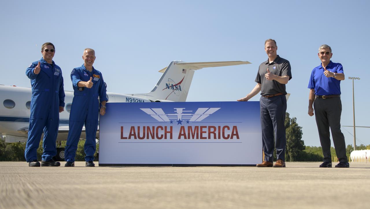NASA astronauts Robert Behnken, left, and Douglas Hurley give a thumbs up with NASA Administrator Jim Bridenstine and Kennedy Space Center Director Bob Cabana, right, after the crew arrived at the Launch and Landing Facility at NASA’s Kennedy Space Center ahead of SpaceX’s Demo-2 mission, Wednesday, May 20, 2020, in Florida. NASA’s SpaceX Demo-2 mission is the first launch with astronauts of the SpaceX Crew Dragon spacecraft and Falcon 9 rocket to the International Space Station as part of the agency’s Commercial Crew Program. The flight test will serve as an end-to-end demonstration of SpaceX’s crew transportation system. Behnken and Hurley are scheduled to launch at 4:33 p.m. EDT on Wednesday, May 27, from Launch Complex 39A at the Kennedy Space Center. A new era of human spaceflight is set to begin as American astronauts once again launch on an American rocket from American soil to low-Earth orbit for the first time since the conclusion of the Space Shuttle Program in 2011.  Photo Credit: (NASA/Bill Ingalls)