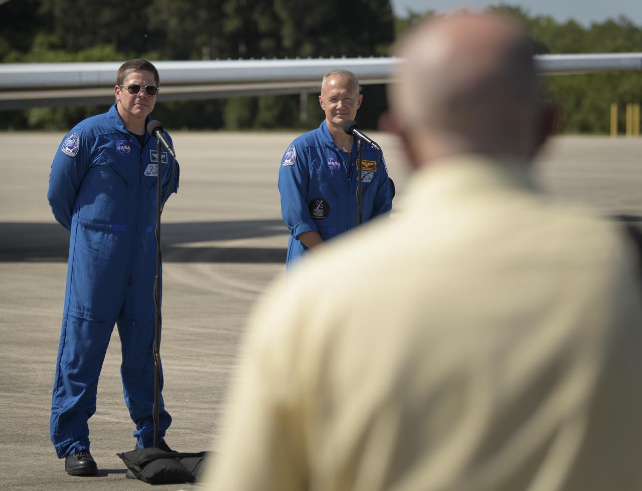 NASA astronauts Robert Behnken, left, and Douglas Hurley speak to members of the media after arriving at the Launch and Landing Facility at NASA’s Kennedy Space Center ahead of SpaceX’s Demo-2 mission, Wednesday, May 20, 2020, in Florida. NASA’s SpaceX Demo-2 mission is the first launch with astronauts of the SpaceX Crew Dragon spacecraft and Falcon 9 rocket to the International Space Station as part of the agency’s Commercial Crew Program. The flight test will serve as an end-to-end demonstration of SpaceX’s crew transportation system. Behnken and Hurley are scheduled to launch at 4:33 p.m. EDT on Wednesday, May 27, from Launch Complex 39A at the Kennedy Space Center. A new era of human spaceflight is set to begin as American astronauts once again launch on an American rocket from American soil to low-Earth orbit for the first time since the conclusion of the Space Shuttle Program in 2011.  Photo Credit: (NASA/Bill Ingalls)