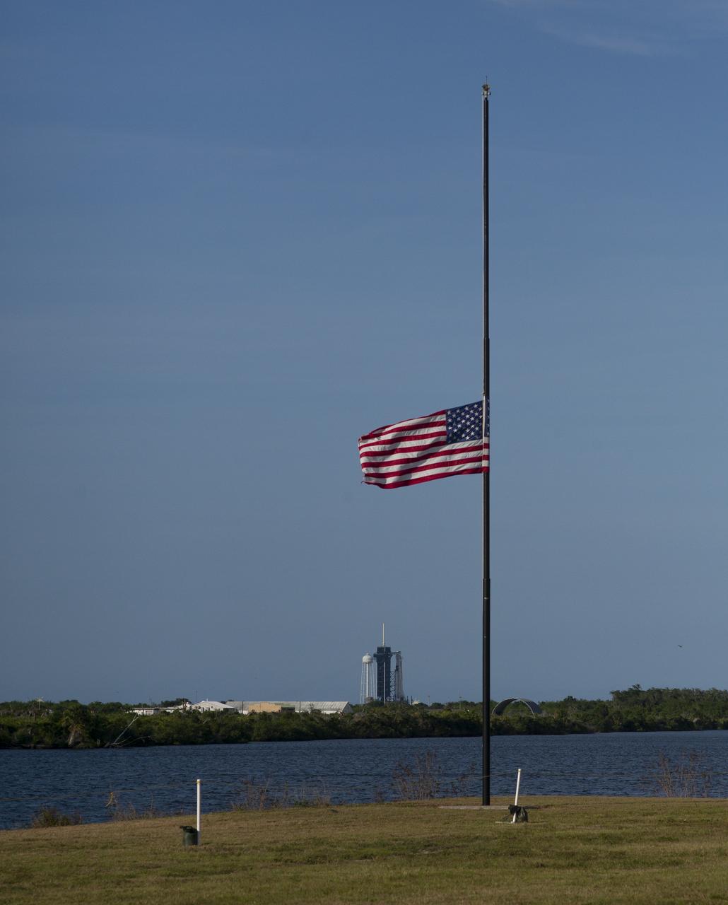 The American flag flies at half-staff next to the countdown clock at NASA’s Kennedy Space Center Press Site, Friday, May 22, 2020, in Florida. President Donald Trump directed on Thursday that flags be lowered to half-staff until sunset on May 24th “as a mark of solemn respect for the victims of the coronavirus pandemic.” NASA’s SpaceX Demo-2 mission is the first launch with astronauts of the SpaceX Crew Dragon spacecraft and Falcon 9 rocket to the International Space Station as part of the agency’s Commercial Crew Program. The test flight serves as an end-to-end demonstration of SpaceX’s crew transportation system. Robert Behnken and Douglas Hurley are scheduled to launch at 4:33 p.m. EDT on Wednesday, May 27, from Launch Complex 39A at the Kennedy Space Center. A new era of human spaceflight is set to begin as American astronauts once again launch on an American rocket from American soil to low-Earth orbit for the first time since the conclusion of the Space Shuttle Program in 2011. Photo Credit: (NASA/Joel Kowsky)