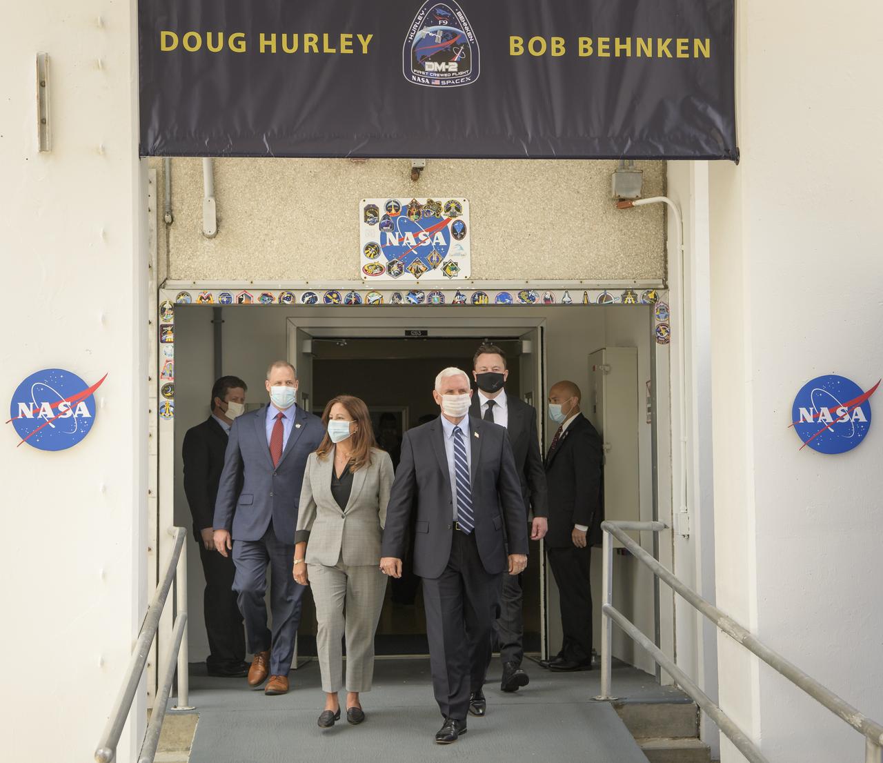 Vice President Mike Pence, and Second Lady Karen Pence, joined by NASA Administrator Jim Bridenstine, left, and Elon Musk, SpaceX Chief Engineer, right, exit the Neil A. Armstrong Operations and Checkout Building ahead of NASA astronauts Douglas Hurley and Robert Behnken departing for Launch Complex 39A to board the SpaceX Crew Dragon spacecraft for the Demo-2 mission launch, Wednesday, May 27, 2020, at NASA’s Kennedy Space Center in Florida. NASA’s SpaceX Demo-2 mission is the first launch with astronauts of the SpaceX Crew Dragon spacecraft and Falcon 9 rocket to the International Space Station as part of the agency’s Commercial Crew Program. The test flight serves as an end-to-end demonstration of SpaceX’s crew transportation system. Behnken and Hurley are scheduled to launch at 4:33 p.m. EDT on Wednesday, May 27, from Launch Complex 39A at the Kennedy Space Center. A new era of human spaceflight is set to begin as American astronauts once again launch on an American rocket from American soil to low-Earth orbit for the first time since the conclusion of the Space Shuttle Program in 2011. Photo Credit: (NASA/Bill Ingalls)