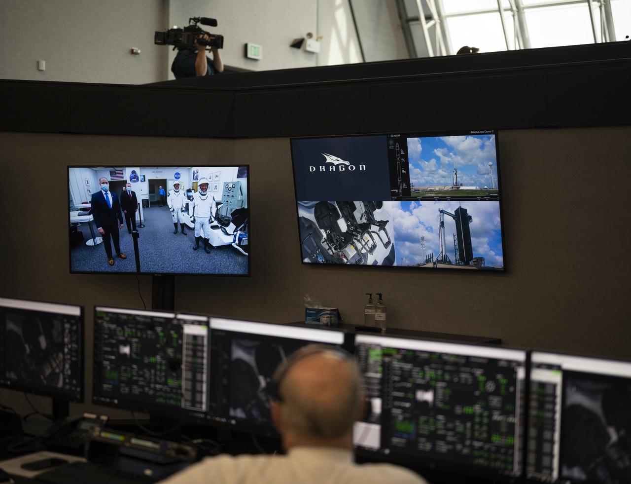 NASA astronauts Robert Behnken and Douglas Hurley are seen after suit-up with NASA Administrator Jim Bridenstine and NASA Deputy Administrator Jim Morhard in the Neil A. Armstrong Operations and Checkout Building on a monitor inside firing room four prior to departing for Launch Complex 39A, Saturday, May 30, 2020, in the Launch Control Center at NASA’s Kennedy Space Center in Florida. NASA’s SpaceX Demo-2 mission is the first launch with astronauts of the SpaceX Crew Dragon spacecraft and Falcon 9 rocket to the International Space Station as part of the agency’s Commercial Crew Program. The test flight serves as an end-to-end demonstration of SpaceX’s crew transportation system. Behnken and Hurley launched at 3:22 p.m. EDT on Saturday, May 30, from Launch Complex 39A at the Kennedy Space Center. A new era of human spaceflight is set to begin as American astronauts once again launch on an American rocket from American soil to low-Earth orbit for the first time since the conclusion of the Space Shuttle Program in 2011. Photo Credit: (NASA/Joel Kowsky)