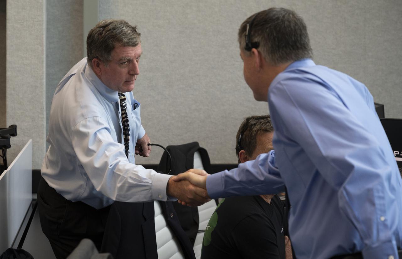 NASA International Space Station Program Manger Kirk Shireman shakes hands with Steve Stich, deputy manager of NASA’s Commercial Crew Program following the launch of a SpaceX Falcon 9 rocket carrying the company's Crew Dragon spacecraft on the Demo-2 mission with NASA astronauts Douglas Hurley and Robert Behnken onboard, Saturday, May 30, 2020, in firing room four of the Launch Control Center at NASA’s Kennedy Space Center in Florida. NASA’s SpaceX Demo-2 mission is the first launch with astronauts of the SpaceX Crew Dragon spacecraft and Falcon 9 rocket to the International Space Station as part of the agency’s Commercial Crew Program. The test flight serves as an end-to-end demonstration of SpaceX’s crew transportation system. Behnken and Hurley launched at 3:22 p.m. EDT on Saturday, May 30, from Launch Complex 39A at the Kennedy Space Center. A new era of human spaceflight is set to begin as American astronauts once again launch on an American rocket from American soil to low-Earth orbit for the first time since the conclusion of the Space Shuttle Program in 2011. Photo Credit: (NASA/Joel Kowsky)