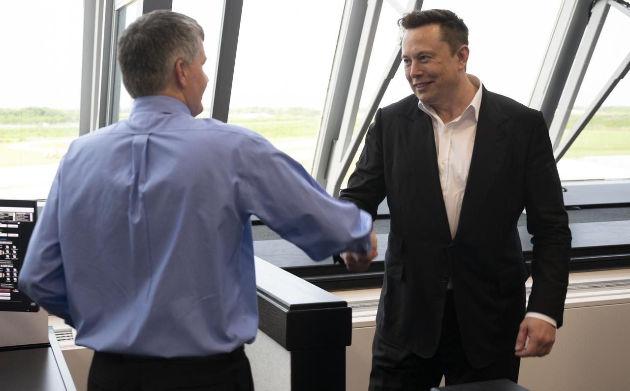 Elon Musk, SpaceX Chief Engineer, shakes hands with Steve Stich, deputy manager of NASA’s Commercial Crew Program, following the launch of a SpaceX Falcon 9 rocket carrying the company's Crew Dragon spacecraft on the Demo-2 mission with NASA astronauts Douglas Hurley and Robert Behnken onboard, Saturday, May 30, 2020, in  firing room four of the Launch Control Center at NASA’s Kennedy Space Center in Florida. NASA’s SpaceX Demo-2 mission is the first launch with astronauts of the SpaceX Crew Dragon spacecraft and Falcon 9 rocket to the International Space Station as part of the agency’s Commercial Crew Program. The test flight serves as an end-to-end demonstration of SpaceX’s crew transportation system. Behnken and Hurley launched at 3:22 p.m. EDT on Saturday, May 30, from Launch Complex 39A at the Kennedy Space Center. A new era of human spaceflight is set to begin as American astronauts once again launch on an American rocket from American soil to low-Earth orbit for the first time since the conclusion of the Space Shuttle Program in 2011. Photo Credit: (NASA/Joel Kowsky)
