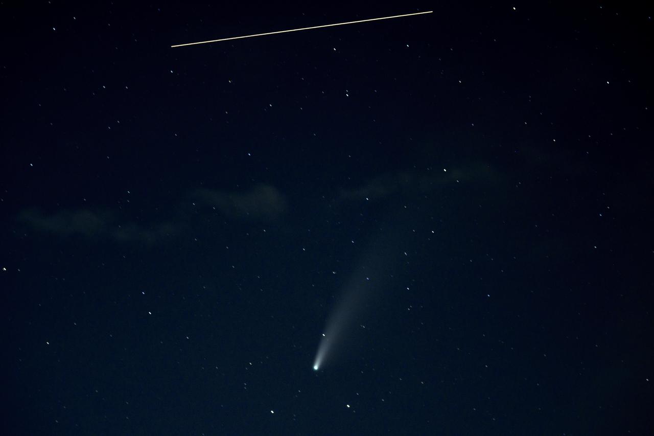 The International Space Station, with a crew of five onboard, is seen in this 10 second exposure above comet NEOWISE, Saturday, July 18, 2020 from Keys Gap, W.Va. The comet was discovered by NASA’s Near-Earth Object Wide-field Infrared Survey Explorer, or NEOWISE, on March 27. Since then, the comet — called comet C/2020 F3 NEOWISE and nicknamed comet NEOWISE — has been spotted by several NASA spacecraft, including Parker Solar Probe, NASA’s Solar and Terrestrial Relations Observatory, the ESA/NASA Solar and Heliospheric Observatory, and astronauts aboard the International Space Station. Onboard the International Space Station are Expedition 63 NASA astronauts Chris Cassidy, Douglas Hurley, Robert Behnken, and Roscosmos cosmonauts Anatoly Ivanishin and Ivan Vagner.  Photo Credit: (NASA/Bill Ingalls)