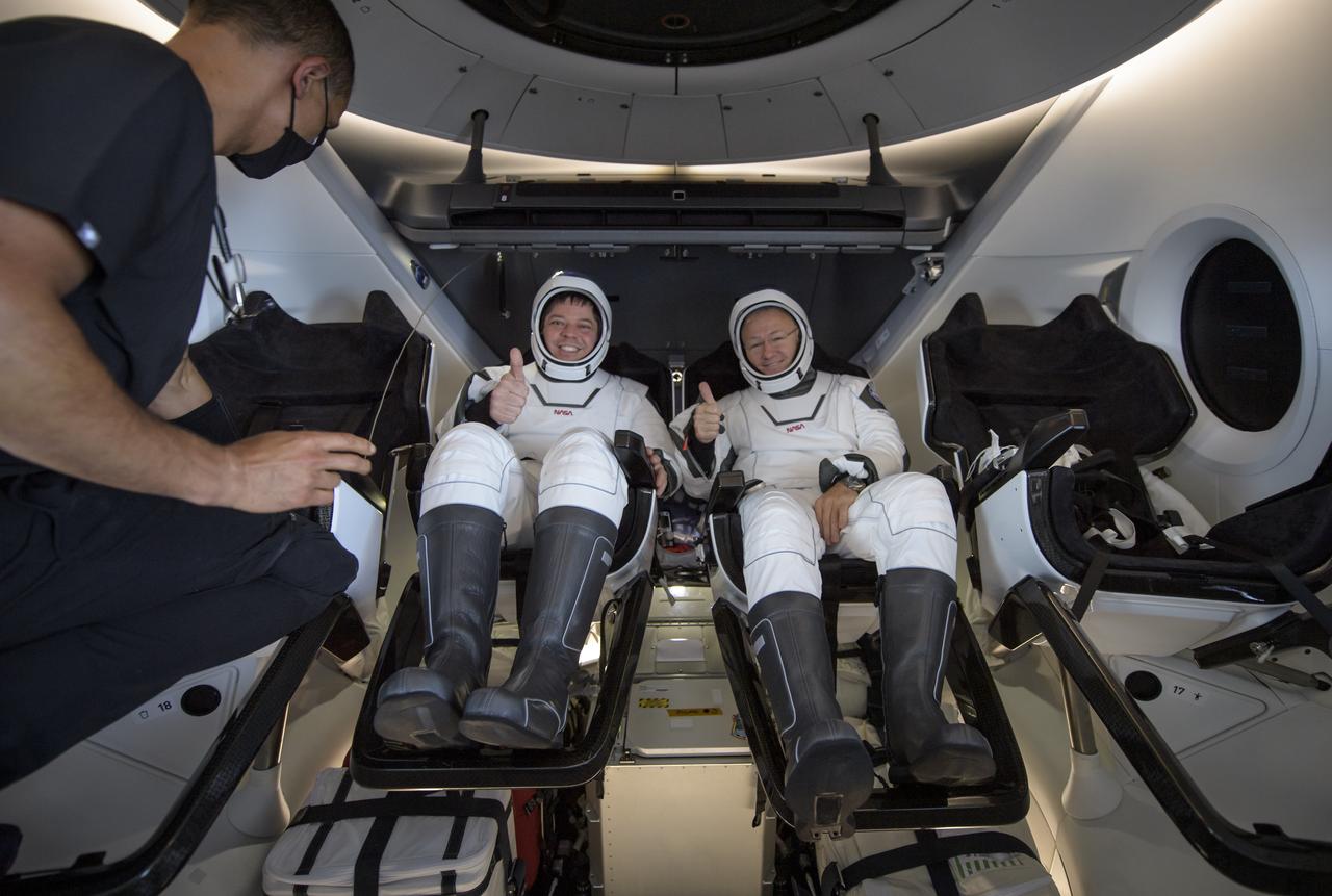 NASA astronauts Robert Behnken, left, and Douglas Hurley are seen inside the SpaceX Crew Dragon Endeavour spacecraft onboard the SpaceX GO Navigator recovery ship shortly after having landed in the Gulf of Mexico off the coast of Pensacola, Florida, Sunday, Aug. 2, 2020. The Demo-2 test flight for NASA's Commercial Crew Program was the first to deliver astronauts to the International Space Station and return them safely to Earth onboard a commercially built and operated spacecraft. Behnken and Hurley returned after spending 64 days in space. Photo Credit: (NASA/Bill Ingalls)
