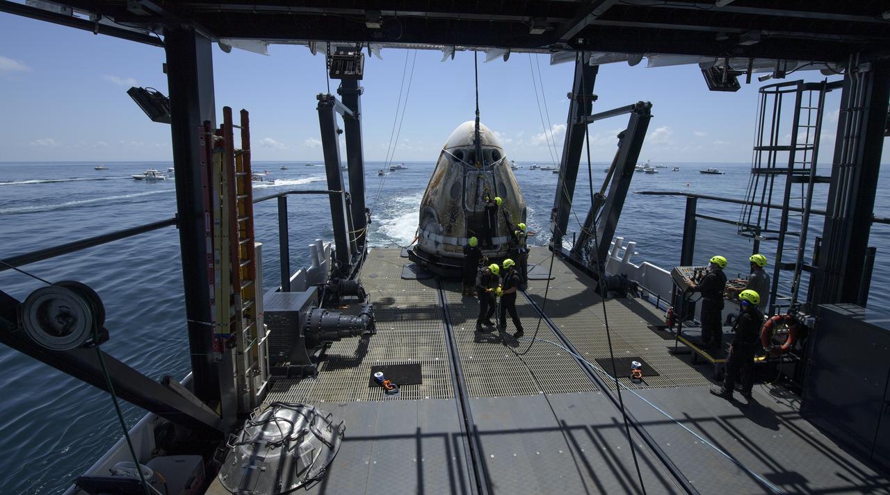 The SpaceX Crew Dragon Endeavour spacecraft is lowered onto the SpaceX GO Navigator recovery ship shortly after it landed with NASA astronauts Robert Behnken and Douglas Hurley onboard in the Gulf of Mexico off the coast of Pensacola, Florida, Sunday, Aug. 2, 2020. The Demo-2 test flight for NASA's Commercial Crew Program was the first to deliver astronauts to the International Space Station and return them safely to Earth onboard a commercially built and operated spacecraft. Behnken and Hurley returned after spending 64 days in space. Photo Credit: (NASA/Bill Ingalls)