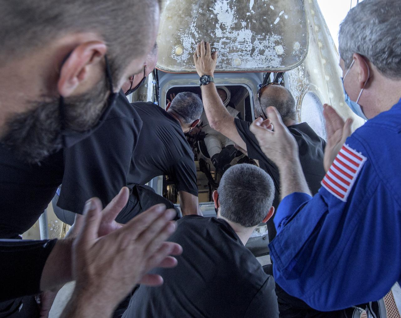 Support teams applaud as after the hatch of the SpaceX Crew Dragon Endeavour spacecraft is opened to allow for egress of NASA astronauts Robert Behnken and Douglas Hurley onto the SpaceX GO Navigator recovery ship shortly the duo landed in the Gulf of Mexico off the coast of Pensacola, Florida, Sunday, Aug. 2, 2020. The Demo-2 test flight for NASA's Commercial Crew Program was the first to deliver astronauts to the International Space Station and return them safely to Earth onboard a commercially built and operated spacecraft. Behnken and Hurley returned after spending 64 days in space. Photo Credit: (NASA/Bill Ingalls)