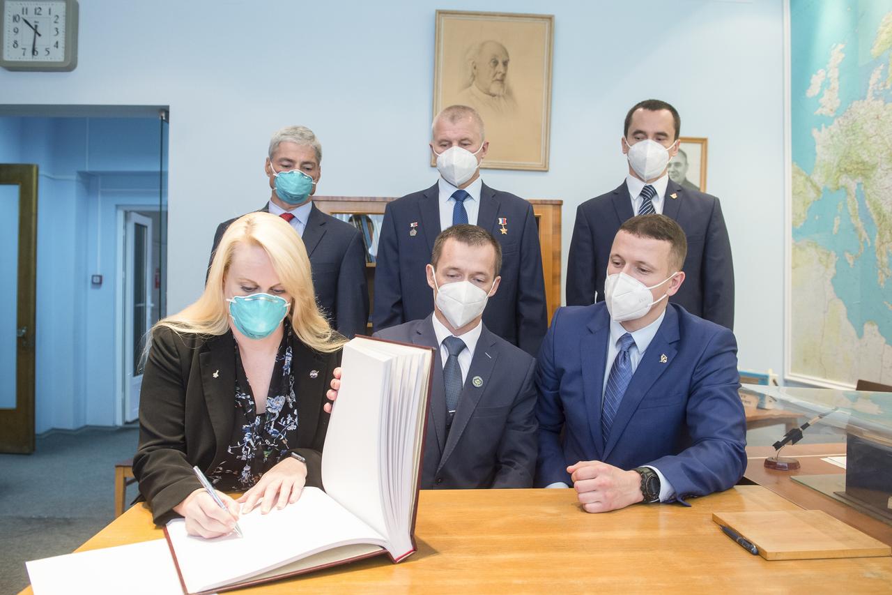Expedition 64 prime crew member NASA astronaut Kate Rubins signs a guest book at the "Memorial working study of Yuri Gagarin" at the Gagarin Cosmonaut Training Center (GCTC), as her crew mates watch, Thursday, Sept. 24, 2020 in Star City, Russia. The memorial study represents Gagarin's working study in the way it was abandoned by Gagarin on March 27, 1968 before leaving for the airfield for training flight that became his last. Photo Credit: (NASA/GCTC/Andrey Shelepin)