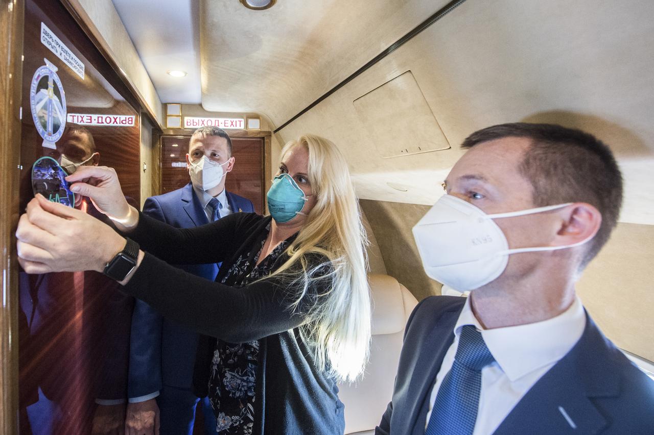Expedition 64 prime crew member, NASA astronaut Kate Rubins, center, affixes an Expedition 64 sticker inside the airplane that delivered her and her crew mates Russian cosmonaut Sergey Ryzhikov of Roscosmos, front, and Russian cosmonaut Sergey Kud-Sverchkov of Roscosmos to Baikonur, Kazakhstan from the Gagarin Cosmonaut Training Center, Sunday, Sept. 27, 2020. They are scheduled to launch from the Baikonur Cosmosdrome on a Soyuz rocket October 14. Photo Credit: (NASA/GCTC/Andrey Shelepin)