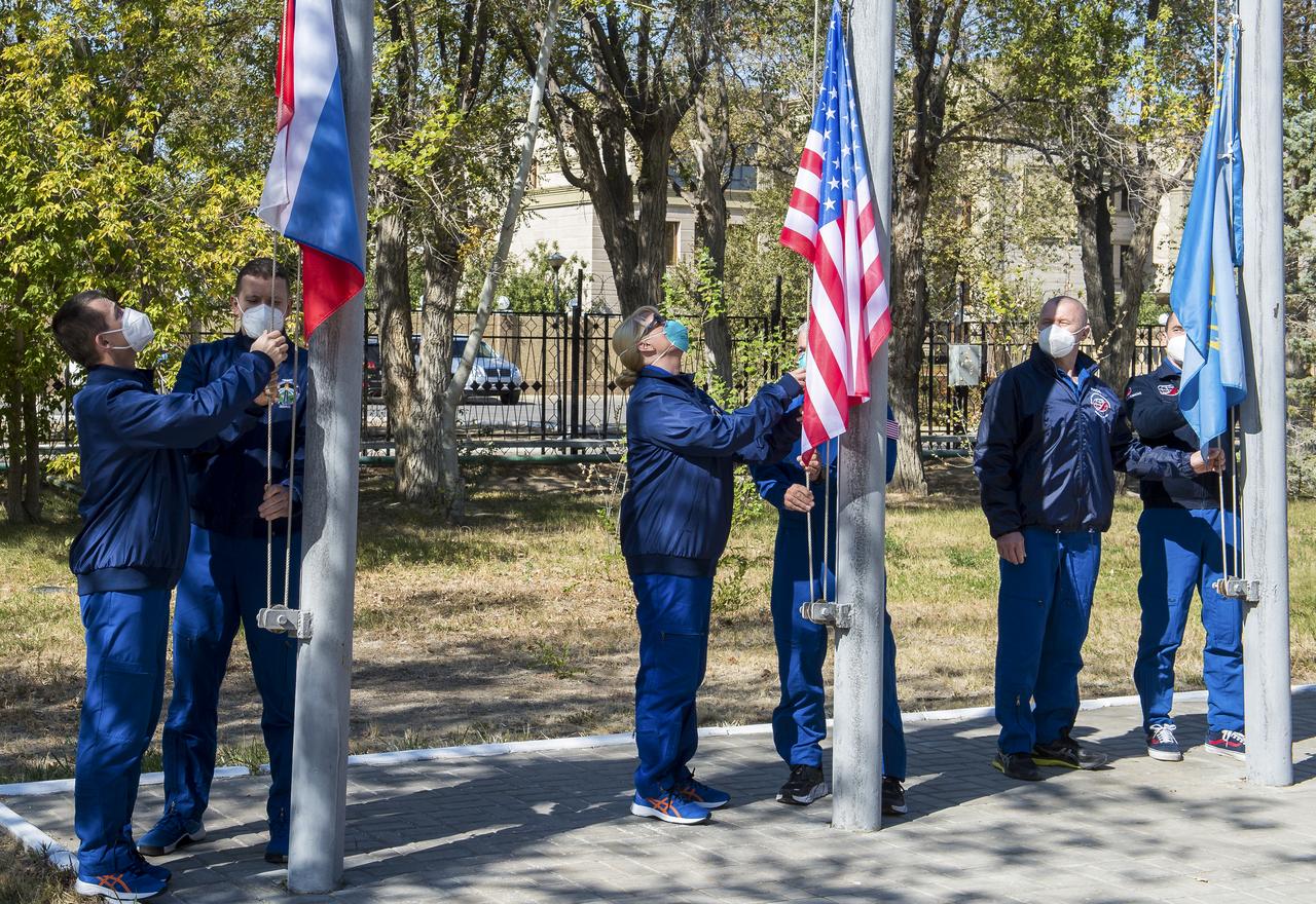 The Expedition 64 prime and backup crew members raise the flags of Russia, the United States, and Kazakhstan, Tuesday, Sept. 29, 2020, in traditional ceremonies outside the Cosmonaut Hotel in Baikonur, Kazakhstan. From left to right are Expedition 64 prime crew members Sergey Ryzhikov and Sergey Kud-Sverchkov of Roscosmos, prime crew member Kate Rubins, and her backup, Mark Vande Hei of NASA, and backup crew members Oleg Novitskiy and Petr Dubov of Roscosmos. Ryzhikov, Kud-Sverchkov, and Rubins are scheduled to launch in their Soyuz MS-17 spacecraft on October 14 for their mission to the International Space Station. Photo Credit: (NASA/GCTC/Andrey Shelepin)