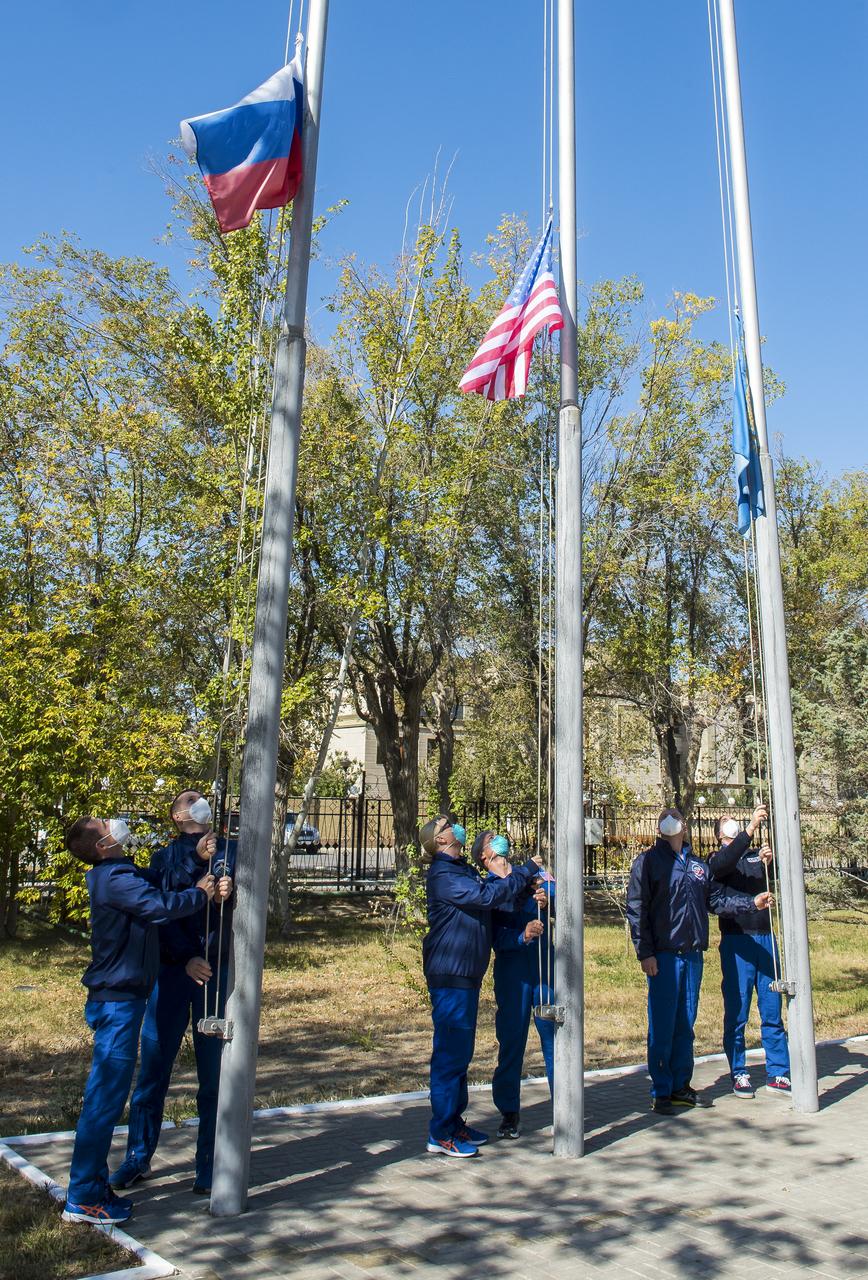 The Expedition 64 prime and backup crew members raise the flags of Russia, the United States, and Kazakhstan, Tuesday, Sept. 29, 2020, in traditional ceremonies outside the Cosmonaut Hotel in Baikonur, Kazakhstan. From left to right are Expedition 64 prime crew members Sergey Ryzhikov and Sergey Kud-Sverchkov of Roscosmos, prime crew member Kate Rubins, and her backup, Mark Vande Hei of NASA, and backup crew members Oleg Novitskiy and Petr Dubrov of Roscosmos. Ryzhikov, Kud-Sverchkov, and Rubins are scheduled to launch in their Soyuz MS-17 spacecraft on October 14 for their mission to the International Space Station. Photo Credit: (NASA/GCTC/Andrey Shelepin)