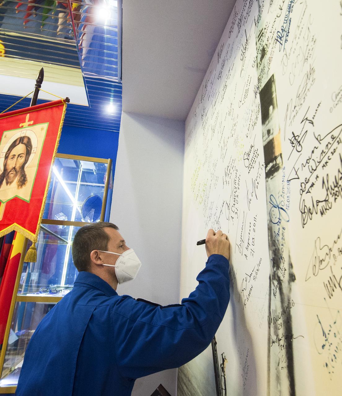 Expedition 64 Russian cosmonaut Sergey Ryzhikov of Roscosmos signs his name to a wall mural bearing the picture of a Soyuz launch at the Baikonur Cosmodrome Museum, Wednesday, Oct. 7, 2020, at the Baikonur Cosmodrome in Kazakhstan. Ryzhikov, Sergey Kud-Sverchkov of Roscosmos, and Kate Rubins of NASA are scheduled to launch to the International Space Station aboard the Soyuz MS-17 spacecraft on October 14. Photo Credit: (NASA/GCTC/Andrey Shelepin)