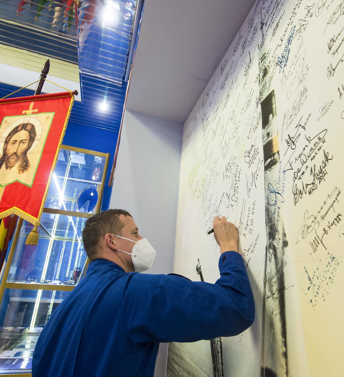 Expedition 64 Russian cosmonaut Sergey Kud-Sverchkov of Roscosmos signs his name to a wall mural bearing the picture of a Soyuz launch at the Baikonur Cosmodrome Museum, Wednesday, Oct. 7, 2020, at the Baikonur Cosmodrome in Kazakhstan. Kud-Sverchkov, Sergey Ryzhikov of Roscosmos, and Kate Rubins of NASA are scheduled to launch to the International Space Station aboard the Soyuz MS-17 spacecraft on October 14. Photo Credit: (NASA/GCTC/Andrey Shelepin)