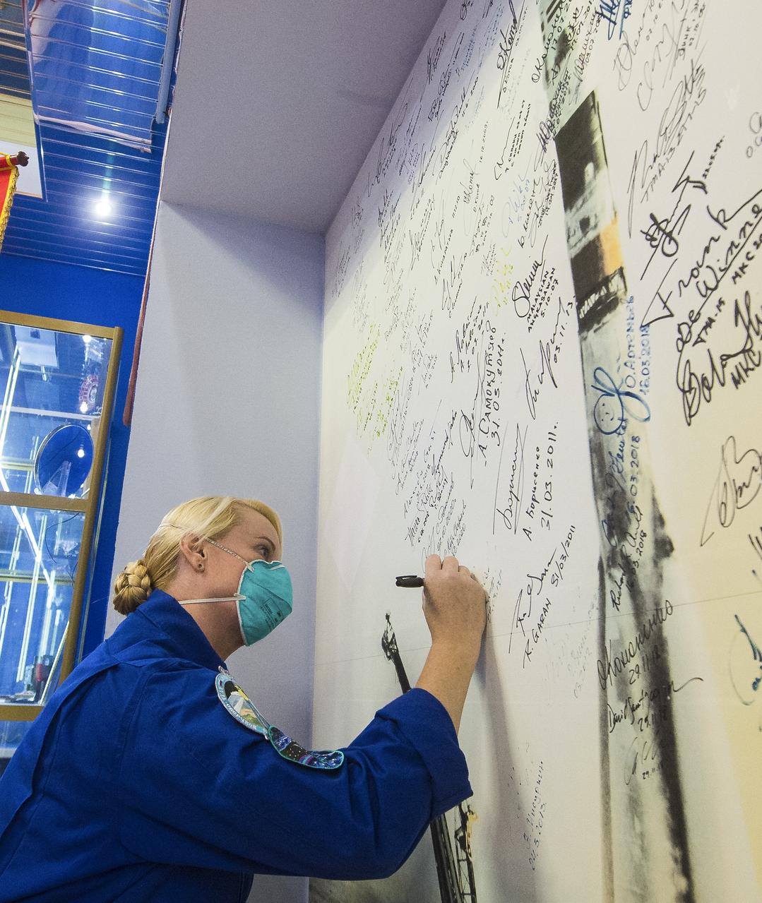 Expedition 64 NASA astronaut Kate Rubins signs her name to a wall mural bearing the picture of a Soyuz launch at the Baikonur Cosmodrome Museum, Wednesday, Oct. 7, 2020, at the Baikonur Cosmodrome in Kazakhstan. Rubins and Sergey Ryzhikov and Sergey Kud-Sverchkov of Roscosmos are scheduled to launch to the International Space Station aboard the Soyuz MS-17 spacecraft on October 14. Photo Credit: (NASA/GCTC/Andrey Shelepin)