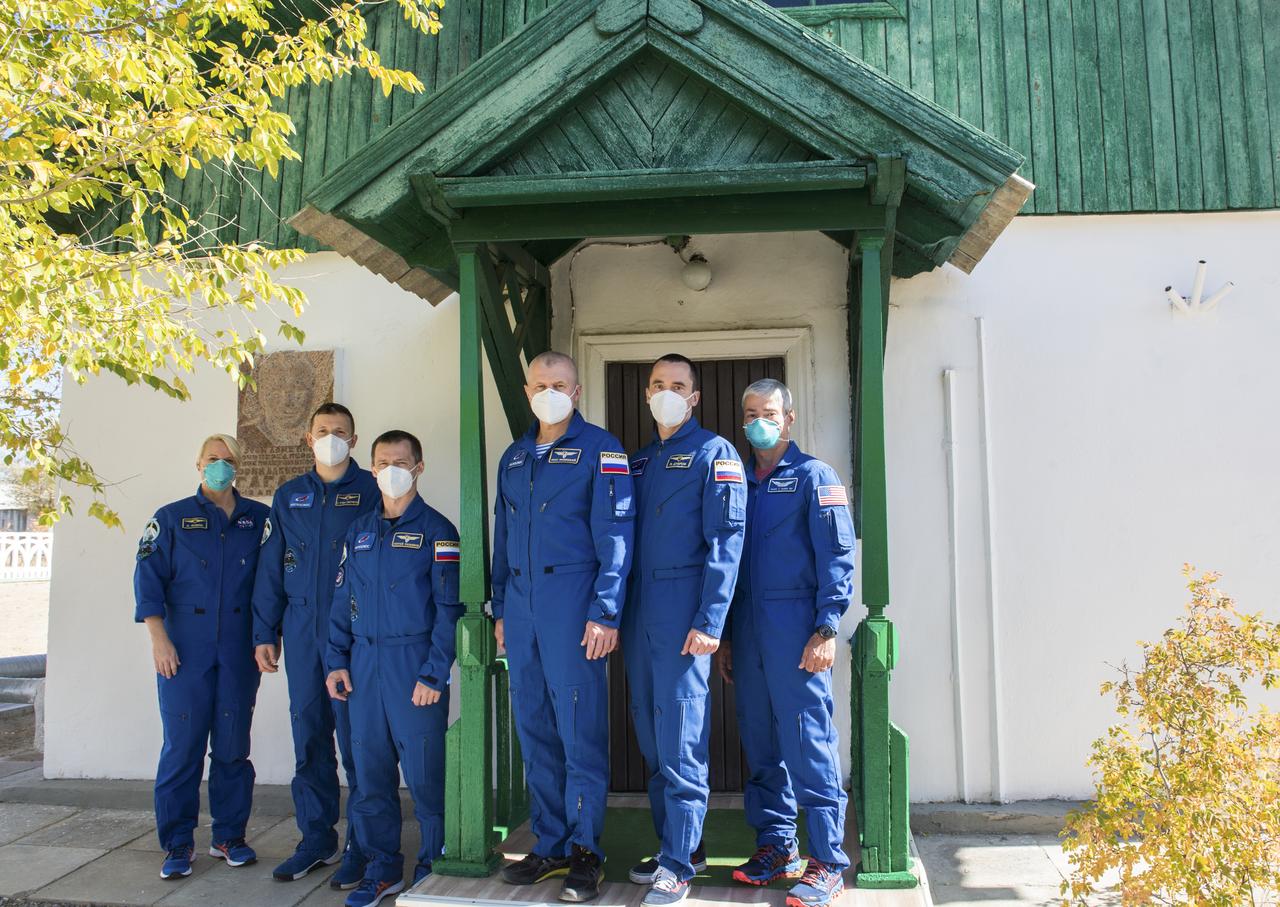The Expedition 64 prime and backup crew members pose for a picture outside of the cottage where Yuri Gagarin slept the night before his historic flight on April 12, 1961 to become the first human in space, Wednesday, Oct. 7, 2020, at the Baikonur Cosmodrome in Kazakhstan. From left to right are the prime crew members Kate Rubins of NASA, Sergey Kud-Sverchkov of Roscosmos, and Sergey Ryzhikov of Roscosmos, and backup crew members Oleg Novitskiy of Roscosmos, Petr Dubrov of Roscosmos, and Mark Vande Hei of NASA. Rubins, Kud-Sverchkov, and Ryzhikov are scheduled to launch to the International Space Station aboard the Soyuz MS-17 spacecraft on October 14. Photo Credit: (NASA/GCTC/Andrey Shelepin)