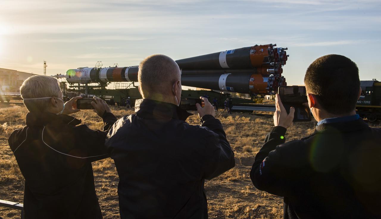 Expedition 64 backup crew members NASA astronaut Mark Vande Hei, left, and Russian cosmonauts Oleg Novitskiy, center, and Petr Dubrov, right, of Roscosmos, take pictures as the Soyuz rocket is rolled out by train to the launch pad at Site 31, Sunday, Oct. 11, 2020, at the Baikonur Cosmodrome in Kazakhstan. Expedition 64 Russian cosmonauts Sergey Ryzhikov and Sergey Kud-Sverchkov of Roscosmos, and NASA astronaut Kate Rubins are scheduled to launch aboard their Soyuz MS-17 spacecraft on Oct. 14 to start a six-month mission onboard the International Space Station.  Photo Credit: (NASA/GCTC/Andrey Shelepin)