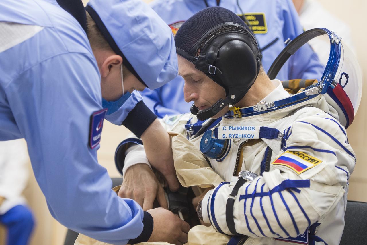 Expedition 64 Russian cosmonaut Sergey Ryzhikov of Roscosmos is helped into his Russian Sokol suit as he and fellow cremates, Sergey Kud-Sverchkov of Roscosmos and Kate Rubins of NASA prepare for their Soyuz launch to the International Space Station Wednesday, Oct. 14, 2020, at the Baikonur Cosmodrome in Kazakhstan.  The trio launched at 1:45 a.m. EDT to begin a six-month mission aboard the International Space Station. Photo Credit: (NASA/GCTC/Andrey Shelepin)