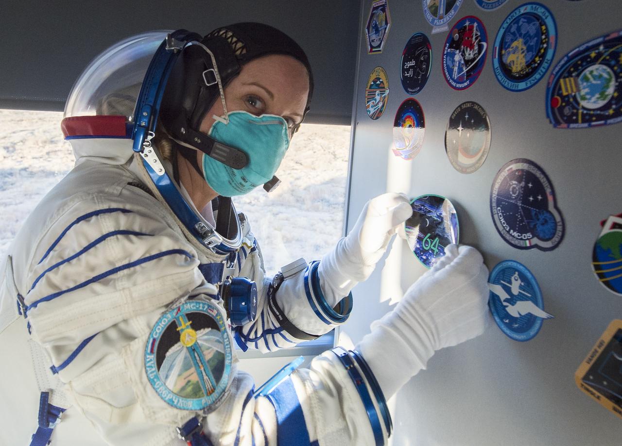 Expedition 64 NASA astronaut Kate Rubins affixes an Expedition 64 sticker inside the bus carrying her and fellow crewmates Russian cosmonauts Sergey Kud-Sverchkov and Sergey Ryzhikov of Roscosmos to the launch pad, Wednesday, Oct. 14, 2020, at the Baikonur Cosmodrome in Kazakhstan. The trio launched at 1:45 a.m. EDT to begin a six-month mission aboard the International Space Station. Photo Credit: (NASA/GCTC/Andrey Shelepin)