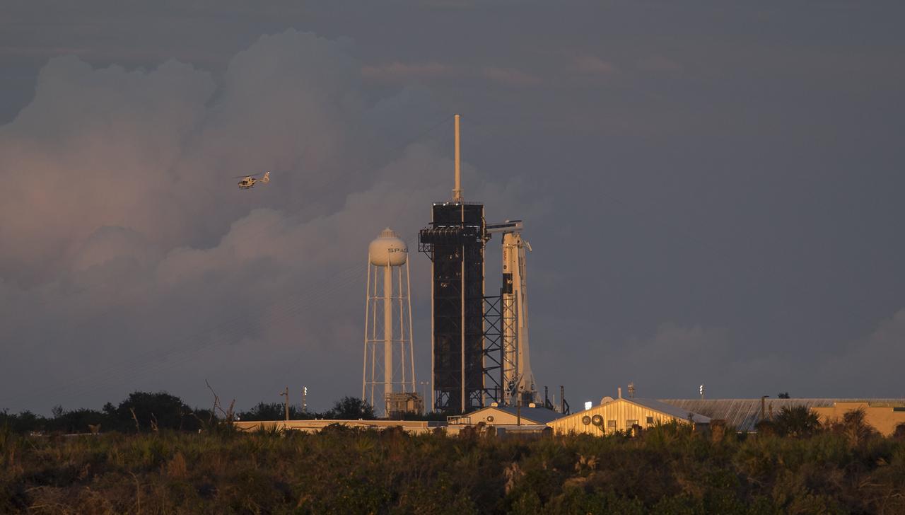 A NASA helicopter is seen flying past a SpaceX Falcon 9 rocket with the company's Crew Dragon spacecraft onboard on the launch pad at Launch Complex 39A as the countdown progresses for the launch of the Crew-1 mission, Sunday, Nov. 15, 2020, at NASA’s Kennedy Space Center in Florida. NASA’s SpaceX Crew-1 mission is the first crew rotation mission of the SpaceX Crew Dragon spacecraft and Falcon 9 rocket to the International Space Station as part of the agency’s Commercial Crew Program. NASA astronauts Mike Hopkins, Victor Glover, and Shannon Walker, and astronaut Soichi Noguchi of the Japan Aerospace Exploration Agency (JAXA) are scheduled to launch at 7:27 p.m. EST, from Launch Complex 39A at the Kennedy Space Center. Photo Credit: (NASA/Joel Kowsky)