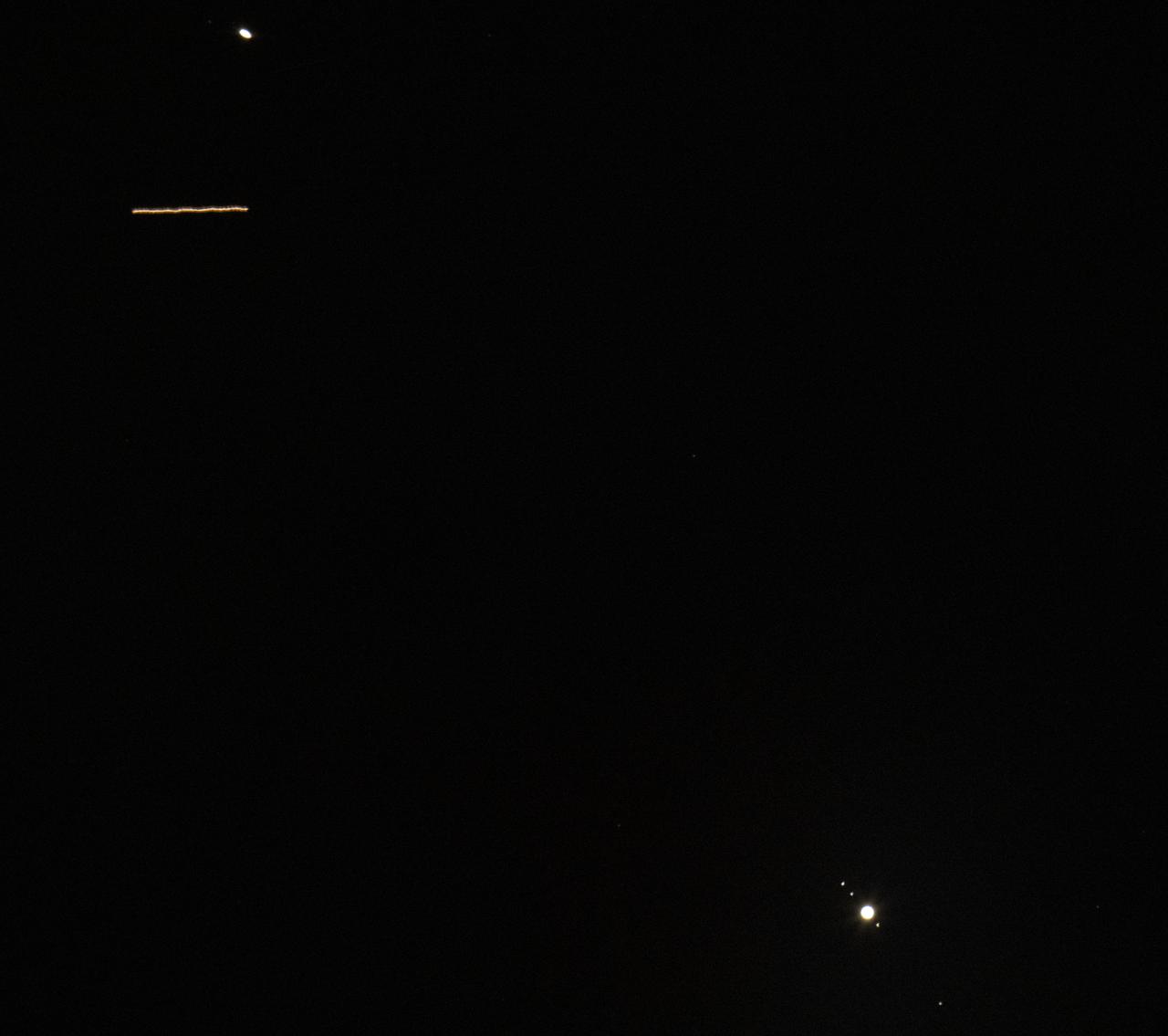 The International Space Station is seen in this third of a second exposure passing between Saturn, top, and Jupiter, bottom, as it flies over Alexandria, Virginia, Friday, Dec. 11, 2020. Onboard are: NASA astronauts Kate Rubins, Shannon Walker, Victor Glover, Mike Hopkins; Japan Aerospace Exploration Agency (JAXA) astronaut Soichi Noguchi; Russian cosmonauts Sergey Ryzhikov, and Sergey Kud-Sverchkov. Saturn and Jupiter are drawing closer to each other in the sky as they head towards a “great conjunction” on December 21, where the two giant planets will appear a tenth of a degree apart.  Photo Credit: (NASA/Joel Kowsky)