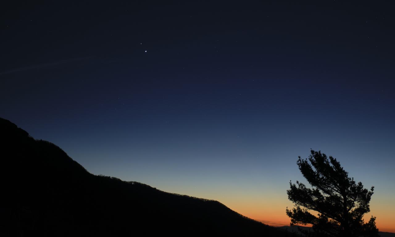 Saturn, top, and Jupiter, below, are seen after sunset from Shenandoah National Park, Sunday, Dec. 13, 2020, in Luray, Virginia. The two planets are drawing closer to each other in the sky as they head towards a “great conjunction” on December 21, where the two giant planets will appear a tenth of a degree apart. Photo Credit: (NASA/Bill Ingalls)