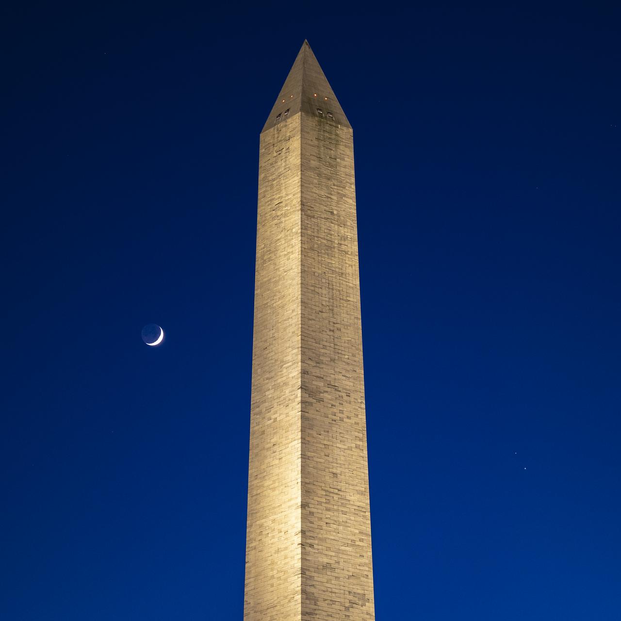 The Moon, left, Saturn, upper right, and Jupiter, lower right, are seen after sunset with the Washington Monument, Thurs. Dec. 17, 2020, in Washington. The two planets are drawing closer to each other in the sky as they head towards a “great conjunction” on December 21, where the two giant planets will appear a tenth of a degree apart. Photo Credit: (NASA/Bill Ingalls)